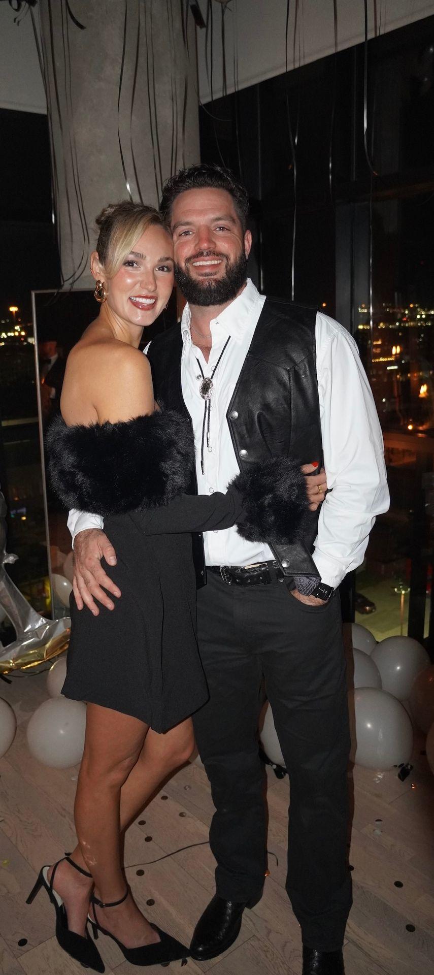 Couple posing together at a party with balloons in the background.